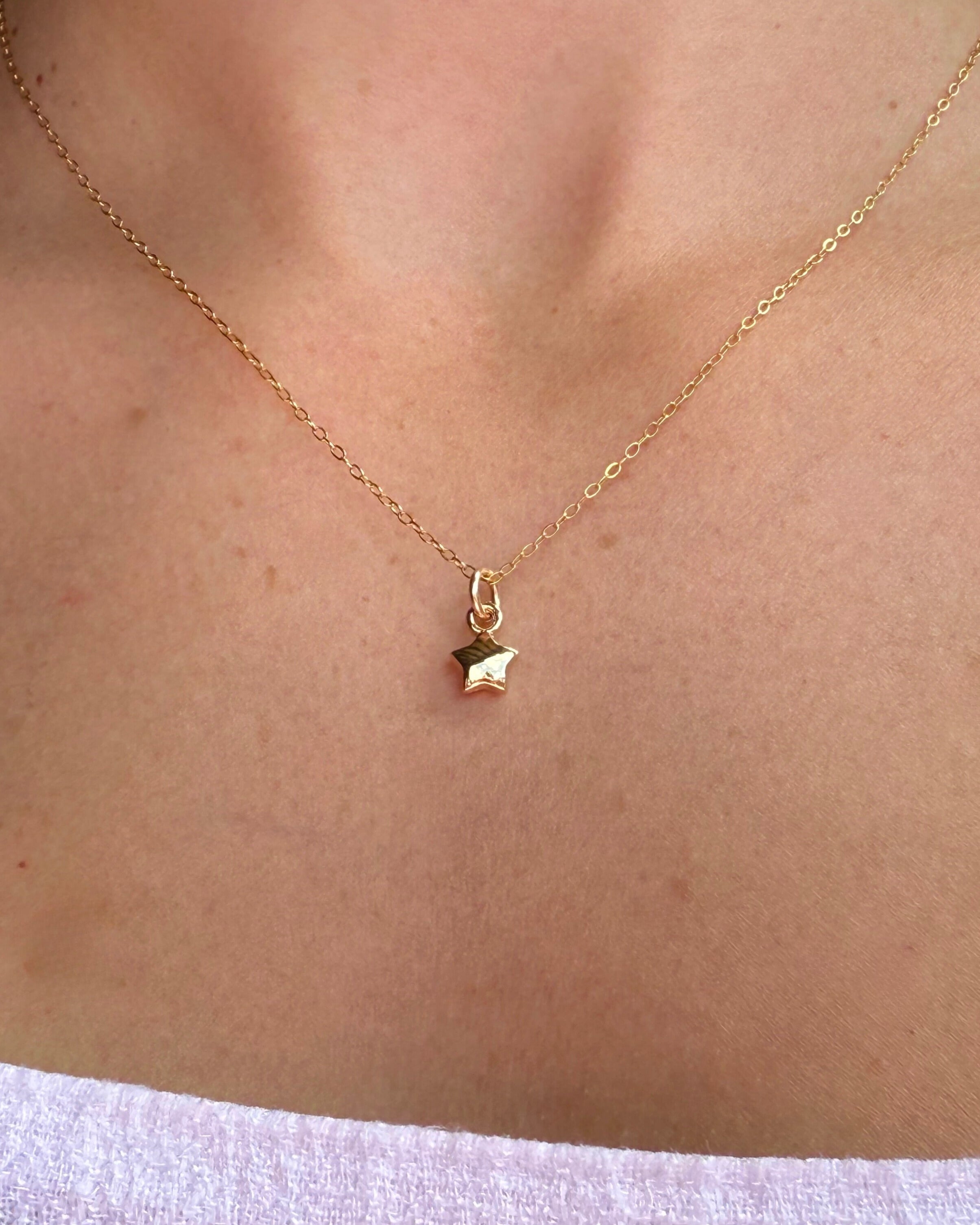 Gold necklace with a star pendant on a person's neck