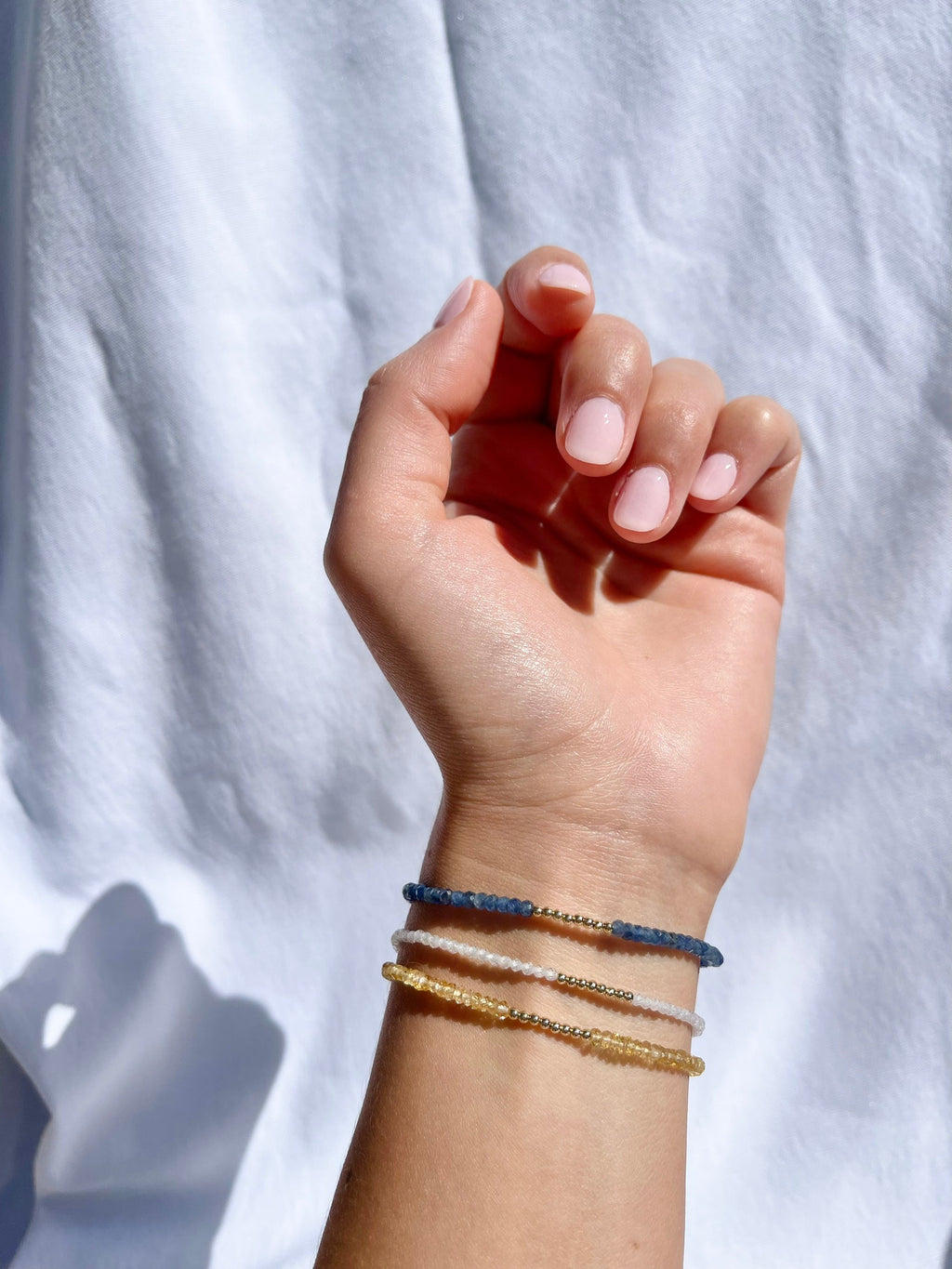 handmade birthstone gem bracelets. citrine, cubic zirconia, and sapphire stacked on a wrist